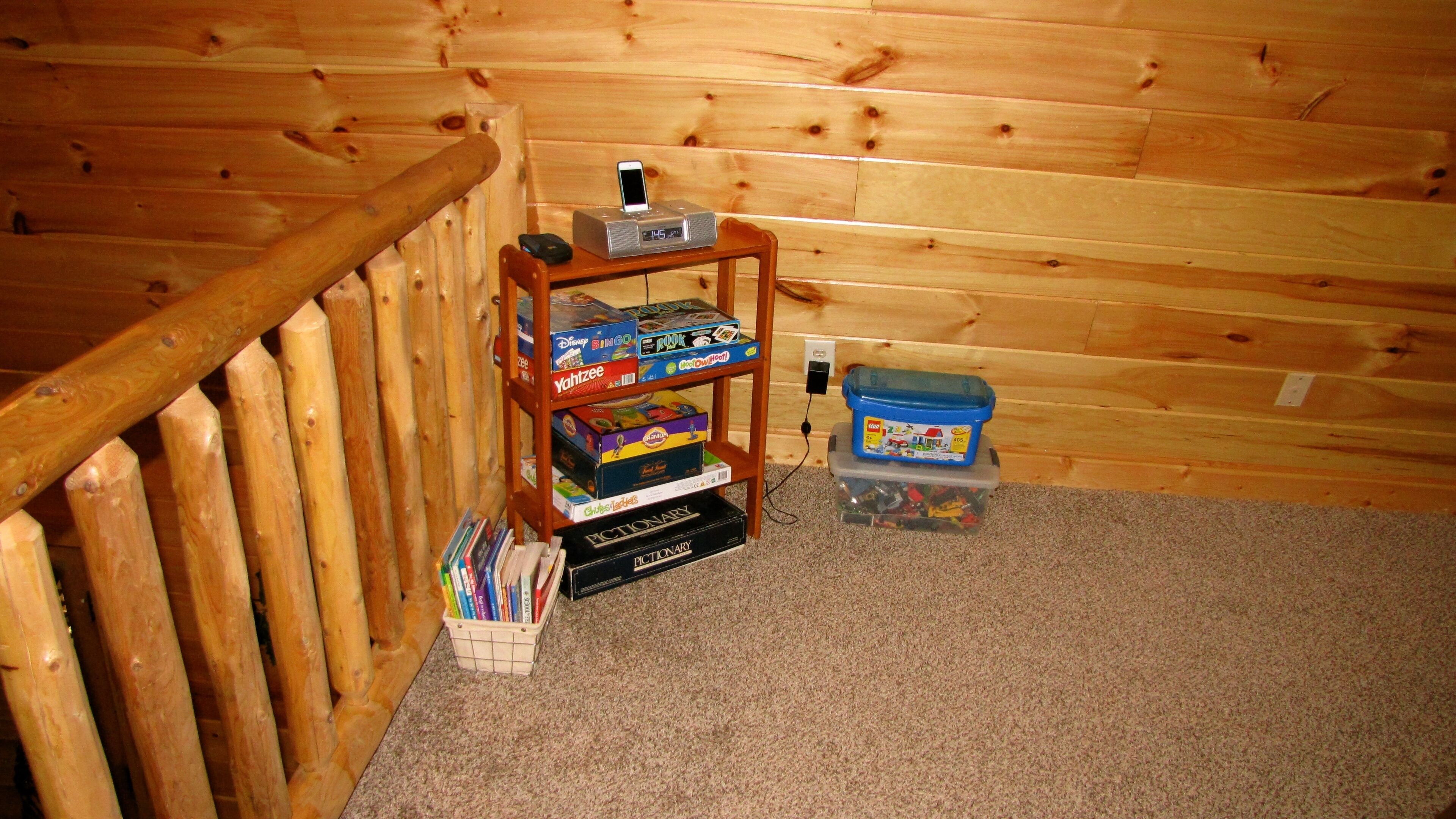 A wooden interior with a shelf holding board games and a dictionary.