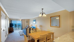 Ein Essbereich mit einem Holztisch und Stühlen, einem Deckenventilator und Meerblick durch die Schiebeglasfenster.