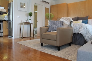 Relax in a comfortable living space with a large bed, a cozy armchair, and a kitchenette.