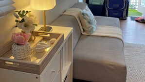 Ein Schlafzimmer mit Bett, Nachttisch, Lampe und einem Fenster mit Jalousien.