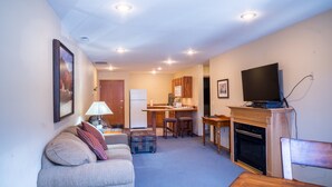 A living room with a sofa, ottoman, and a television on a stand. - In the heart of downtown - Front Street - for Leavenworth's main shopping/dining (Leavenworth)