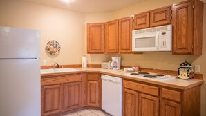 Una cocina con armarios de madera, un refrigerador blanco, un microondas, un lavavajillas y una cafetera.