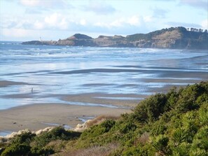 A coastal landscape with a beach, cliffs, and a lighthouse in the distance.