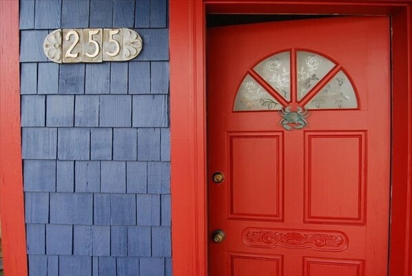 A red door with a decorative fan and a number plaque.
