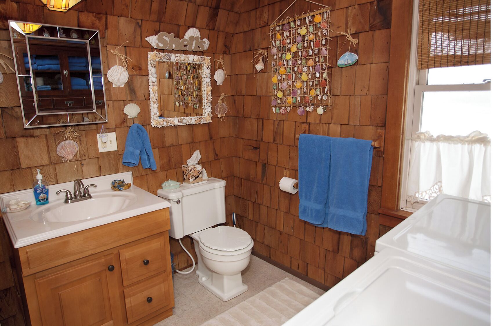 Un baño con paredes y tocador de madera, un espejo, un inodoro y una bañera.