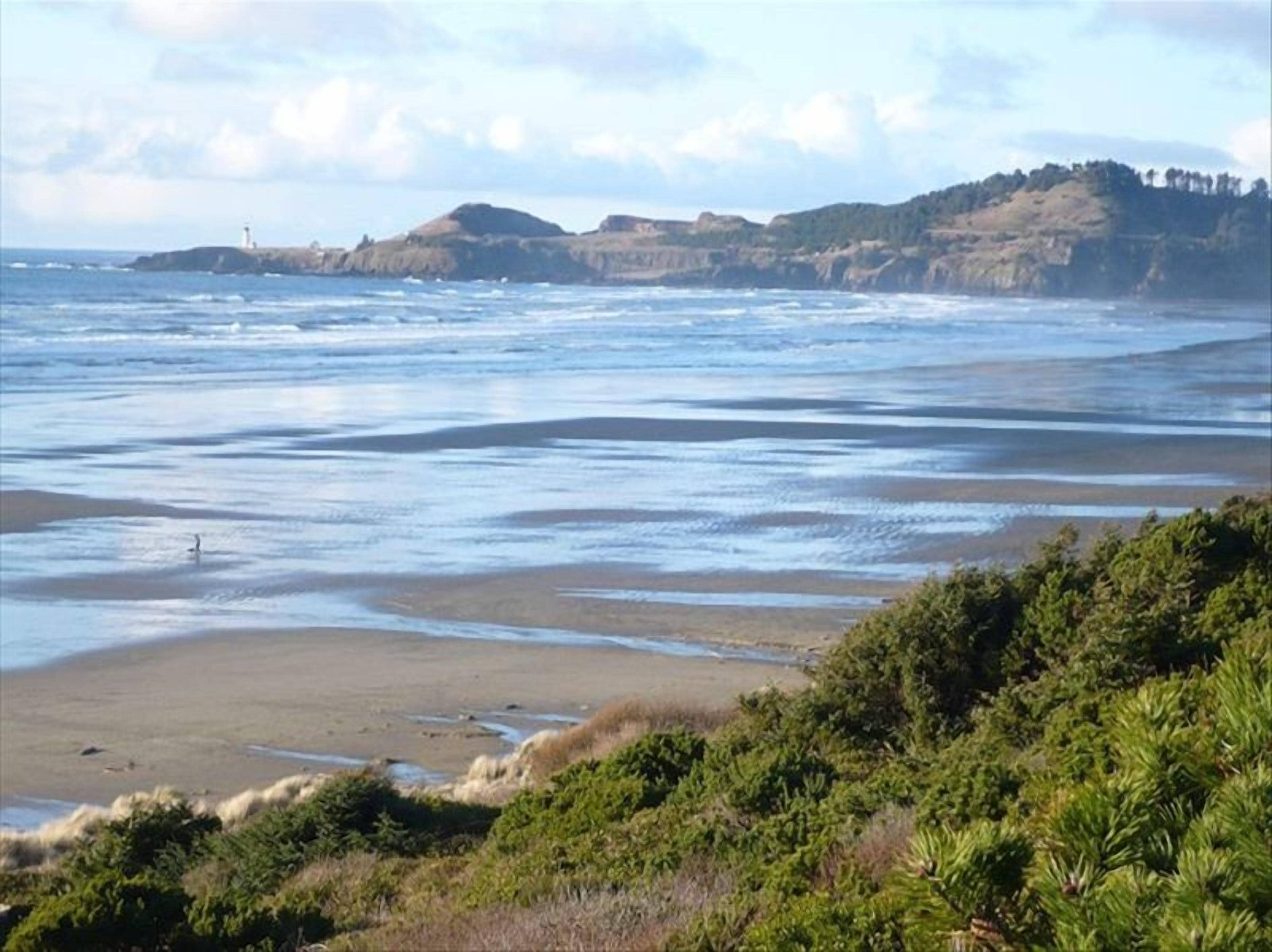 A coastal landscape with a beach, cliffs, and a lighthouse in the distance.