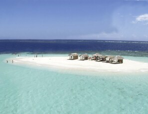 A beach with thatched-roof huts and clear turquoise waters.