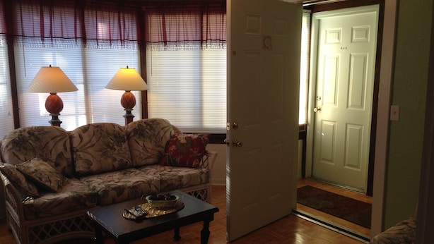 A living room with a sofa, two lamps, a coffee table, and a door with an 'EXIT' sign. - Comfy Queen large 1/1, Near Stetson, Sky Diving, St Johns River, racing, beach (Deland)