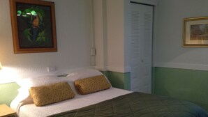 A neatly made bed with a green quilt, two patterned pillows, and a framed picture on the wall. - Comfy Queen large 1/1, Near Stetson, Sky Diving, St Johns River, racing, beach (Deland)
