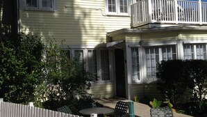 A two-story house with a balcony, a porch with a table and chairs, and a white picket fence. - Comfy Queen large 1/1, Near Stetson, Sky Diving, St Johns River, racing, beach (Deland)