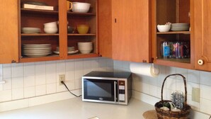 A kitchen with wooden cabinets, a microwave, and various dishes. - Comfy Queen large 1/1, Near Stetson, Sky Diving, St Johns River, racing, beach (Deland)