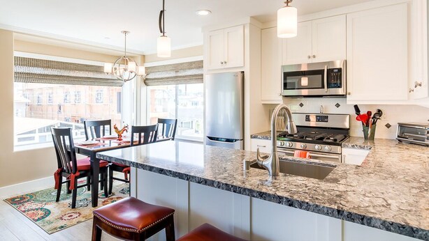 A modern kitchen with white cabinets, stainless steel appliances, and a large island with a sink.