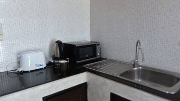Cocina compacta con microondas, tostadora y lavamanos.