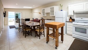 A spacious kitchen with a dining area, white cabinets, and a large window overlooking a beach. - Huntington Beach Furnished Home,  Private Patio, Bikes, Parking & Putting Green (Huntington Beach)