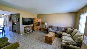 Ein Wohnzimmer mit Fernseher, Holzschrank und einer Couch.