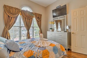 Cozy retreat with a neatly made bed, two large windows, and a mounted television.
