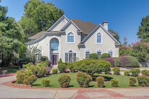 Stately two-story house with a central entrance and beautifully manicured garden.