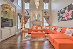 Relax in this stylish living room with a large sofa, flat-screen TV, and decorative fireplace.