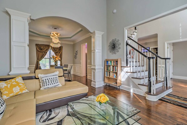 Relax in this inviting living room with a grand staircase, comfortable sofa, and decorative touches.