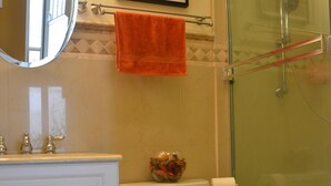 Ein Badezimmer mit Toilette, Waschbecken, Spiegel, Dusche und einem gerahmten Bild an der Wand.