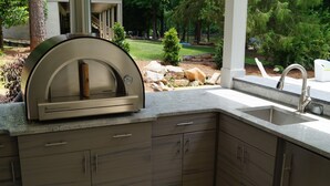 A modern kitchen with a built-in pizza oven, a granite countertop, and a sink. - 5 BDRM Beautiful Peaceful Lake Front Home 3 Kings, 1 Queen, 4 Twins, Pool, Spa (Greensboro)