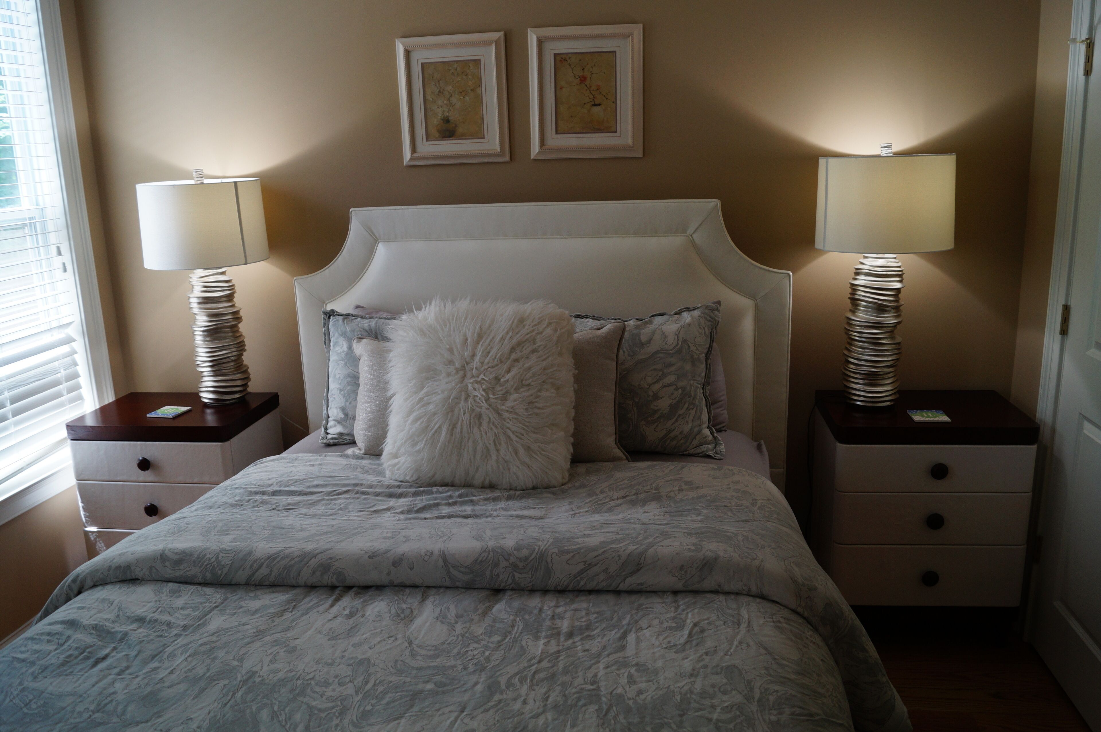 A bedroom with a large bed, two bedside tables, and two wall-mounted lamps.