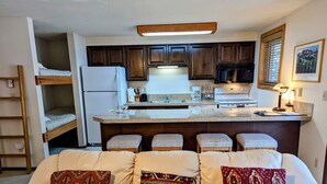 A compact living space with a kitchenette, a sofa with patterned cushions, and a small dining area. - Great 1 (plus) bedroom condo. This is the best location in Ketchum! (Ketchum)