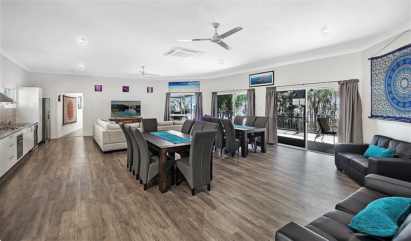 A spacious living area with a dining table, sofas, and a kitchen.