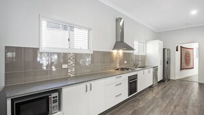 Una cocina moderna con armarios blancos, una campana extractora de acero inoxidable y un lavavajillas empotrado.