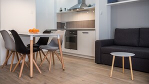 A modern kitchen with a dining table and chairs, a grey sofa, and a small side table.