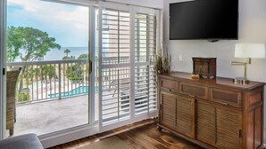 A room with a large sliding glass door leading to a balcony with a pool view.