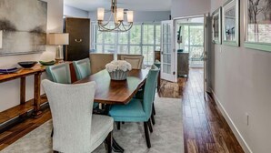 A dining area with a wooden table, teal chairs, and a chandelier.