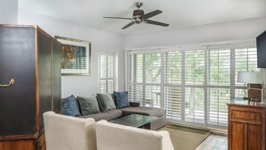 A living room with a sectional sofa, a small table, a cabinet, and a ceiling fan.