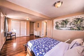 Una camera da letto con un letto, una cassettiera, una sedia e un quadro appeso al muro.