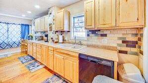 A kitchen with wooden cabinets, a dishwasher, and a tiled backsplash. - Cozy Colorado Springs Home Near Garden of the Gods (Colorado Springs)