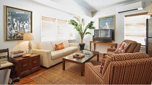 A living room with a sofa, a coffee table, a TV, and a bookshelf. - Historic Suites Hotel in Walkable Downtown between Siesta & Lido Beaches (Sarasota)