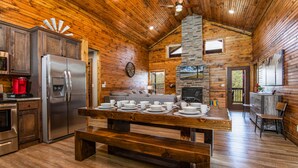 A wooden cabin interior with a kitchen, dining area, and fireplace. - Private hot tub-close to community pool-Pet frndly (Reeds Spring)