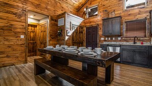 A wooden interior with a dining table set for four, a bench, and a kitchen area with cabinets and a sink. - Private hot tub-close to community pool-Pet frndly (Reeds Spring)