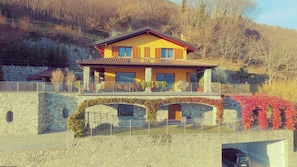 Uma casa de dois andares com uma parede de pedra e uma ponte ligando os dois níveis.