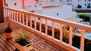 Ein Balkon mit Blick auf weiße Häuser und einen Sonnenuntergang.