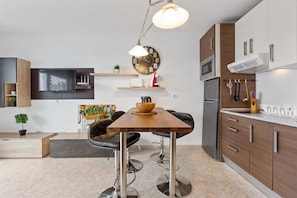 Una cocina moderna con una mesa de madera, taburetes de bar, microondas y horno empotrado.