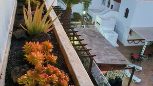 Eine Dachterrasse mit Gartenbeet, Sitzgelegenheiten im Freien und Blick auf die umliegende Architektur.