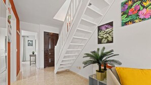 Ein modernes Interieur mit Treppe, Blumentopf und einer gelben Kissen auf einem Sofa.
