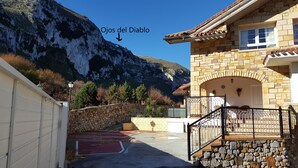 A stone building with a staircase leading to a balcony, a mountain in the background, and a sign pointing to 'Ojos del Diablo'. - Apartment with terrace, and views of the sea and the mountains in Sonabia (Castro Urdiales)