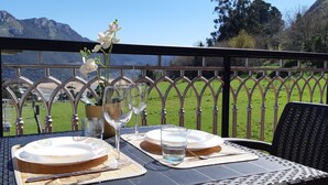 A table set outdoors with a mountain view, a metal railing, and a white flower in a vase. - Apartment with terrace, and views of the sea and the mountains in Sonabia (Castro Urdiales)