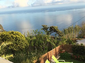 A coastal landscape with a view of the sea, dense greenery, and a wooden fence. - BHF Residences Bordadeira (Calheta)