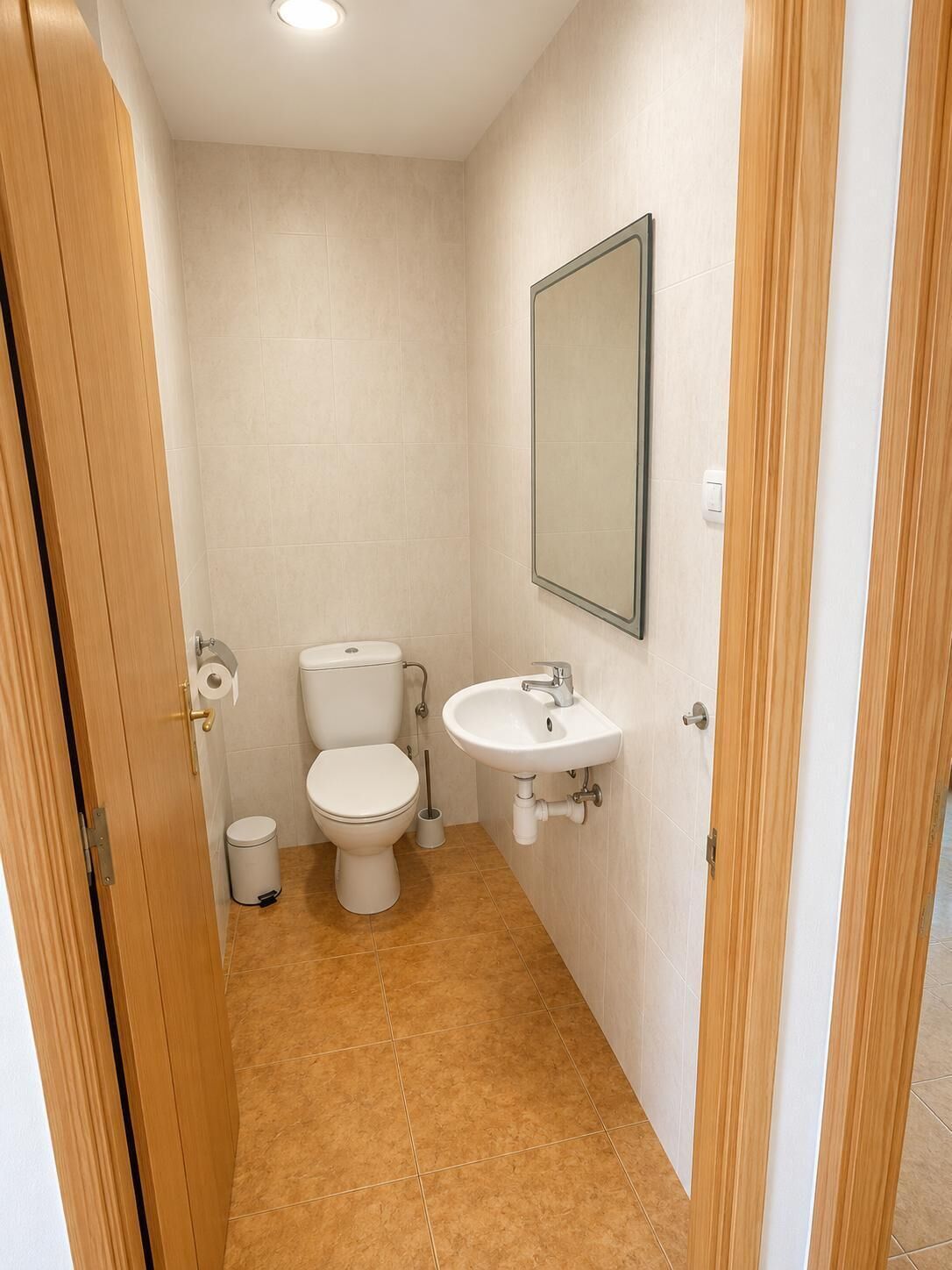 Un baño pequeño y limpio con inodoro, lavamanos y espejo.