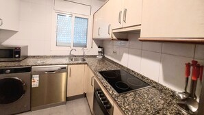 A kitchen with a stainless steel dishwasher, a built-in oven, a granite countertop, and white cabinets. - MAGNIFICENT CHALET, 5 NIMUTOS FROM THE BEACH, WITH POOL, TERRACE AND WIFI. (Miami Platja)