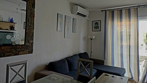 A living room with a sofa, a coffee table, and a TV. There is a wall-mounted air conditioner and a framed picture on the wall. - MAGNIFICENT CHALET, 5 NIMUTOS FROM THE BEACH, WITH POOL, TERRACE AND WIFI. (Miami Platja)