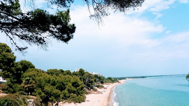 A coastal landscape with a rocky beach, clear blue sea, and dense greenery. - MAGNIFICENT CHALET, 5 NIMUTOS FROM THE BEACH, WITH POOL, TERRACE AND WIFI. (Miami Platja)